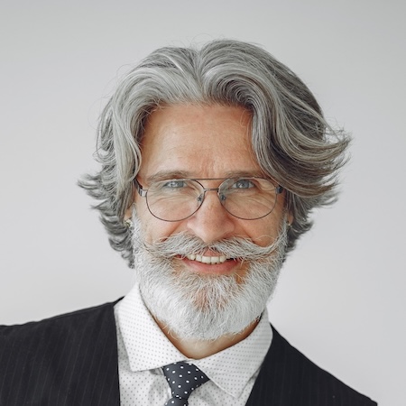 Portrait of a smiling older man with gray hair, glasses and a suit